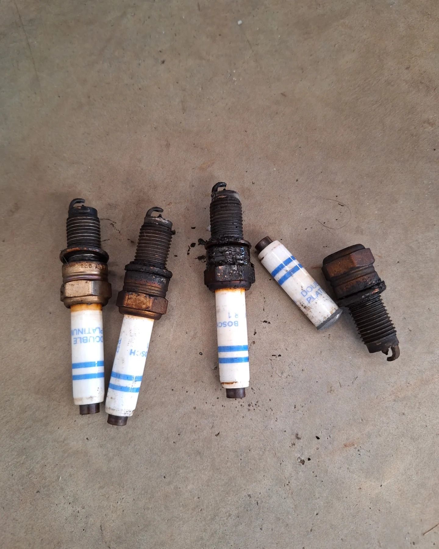 A group of spark plugs are sitting on a concrete surface.