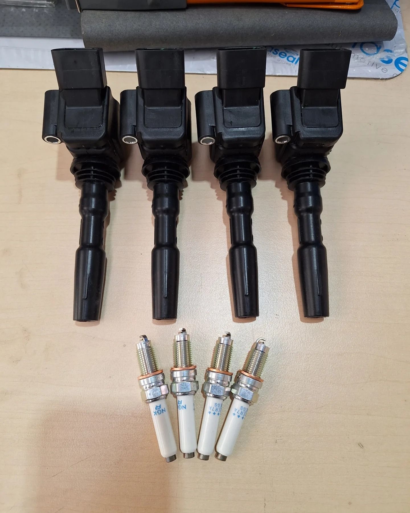 Four ignition coils and four spark plugs on a table