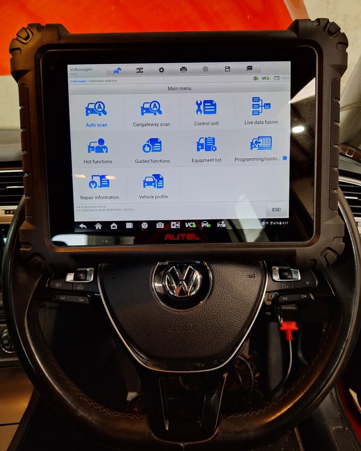 A tablet is sitting on top of a vw steering wheel.