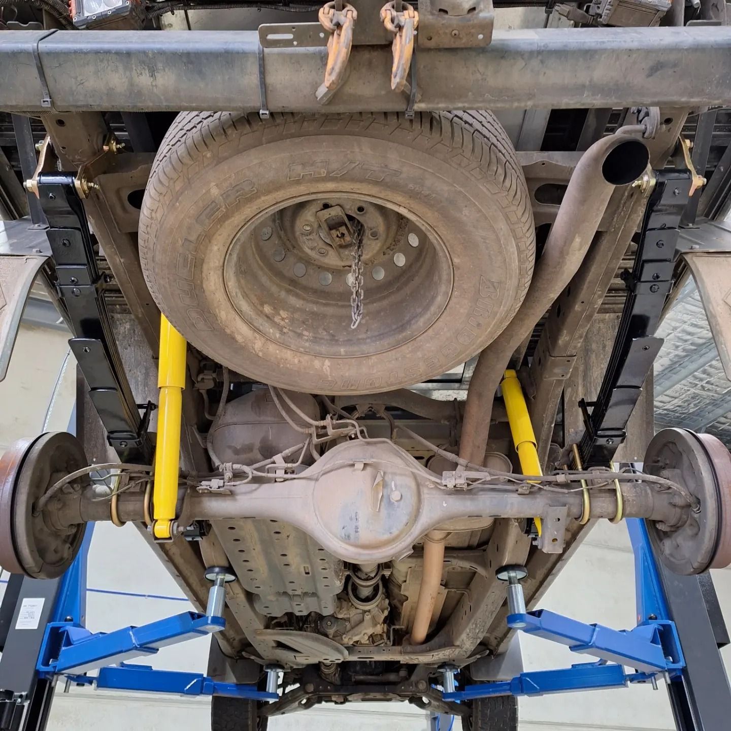 The underside of a truck is shown on a lift.