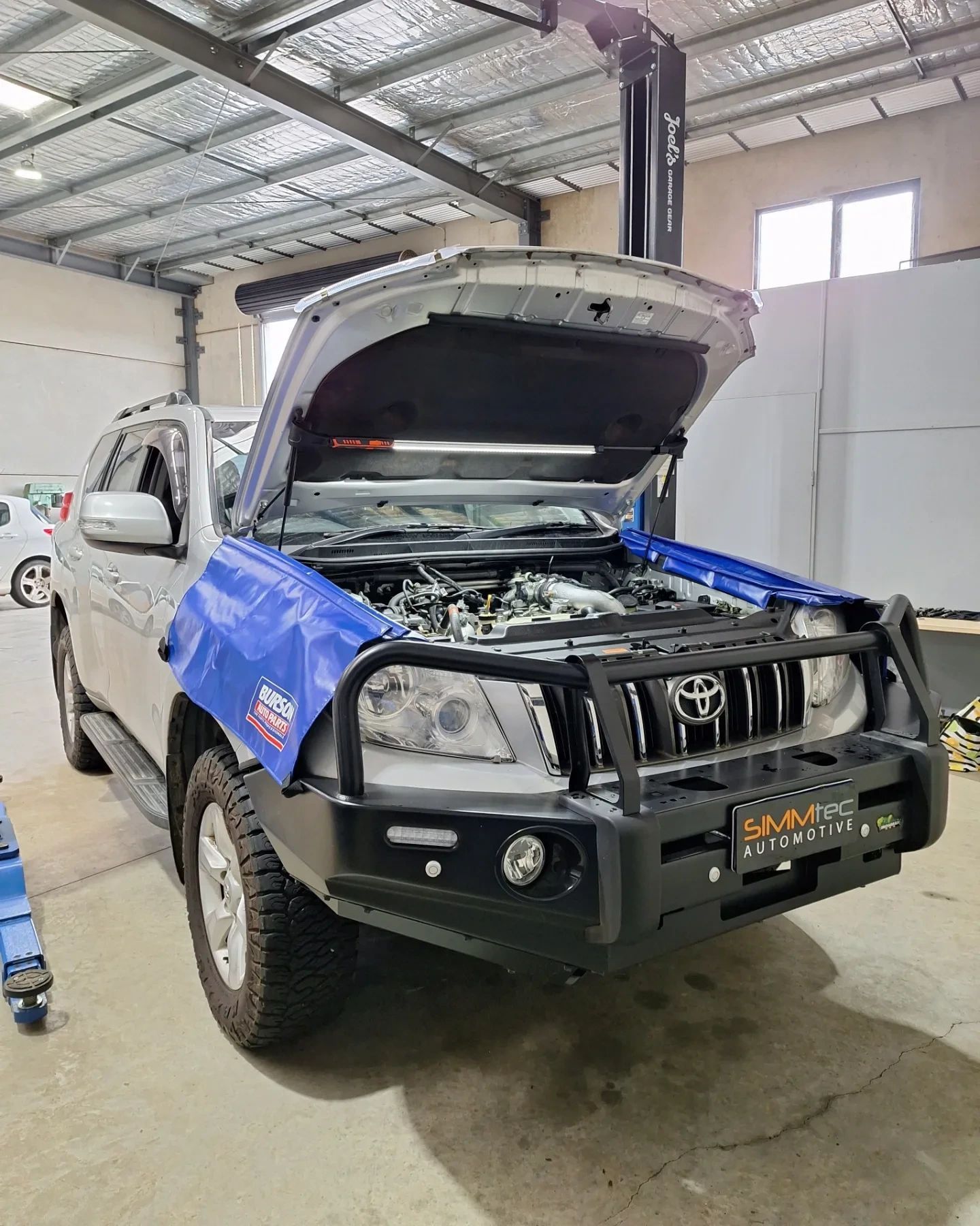 A toyota land cruiser with its hood open in a garage.
