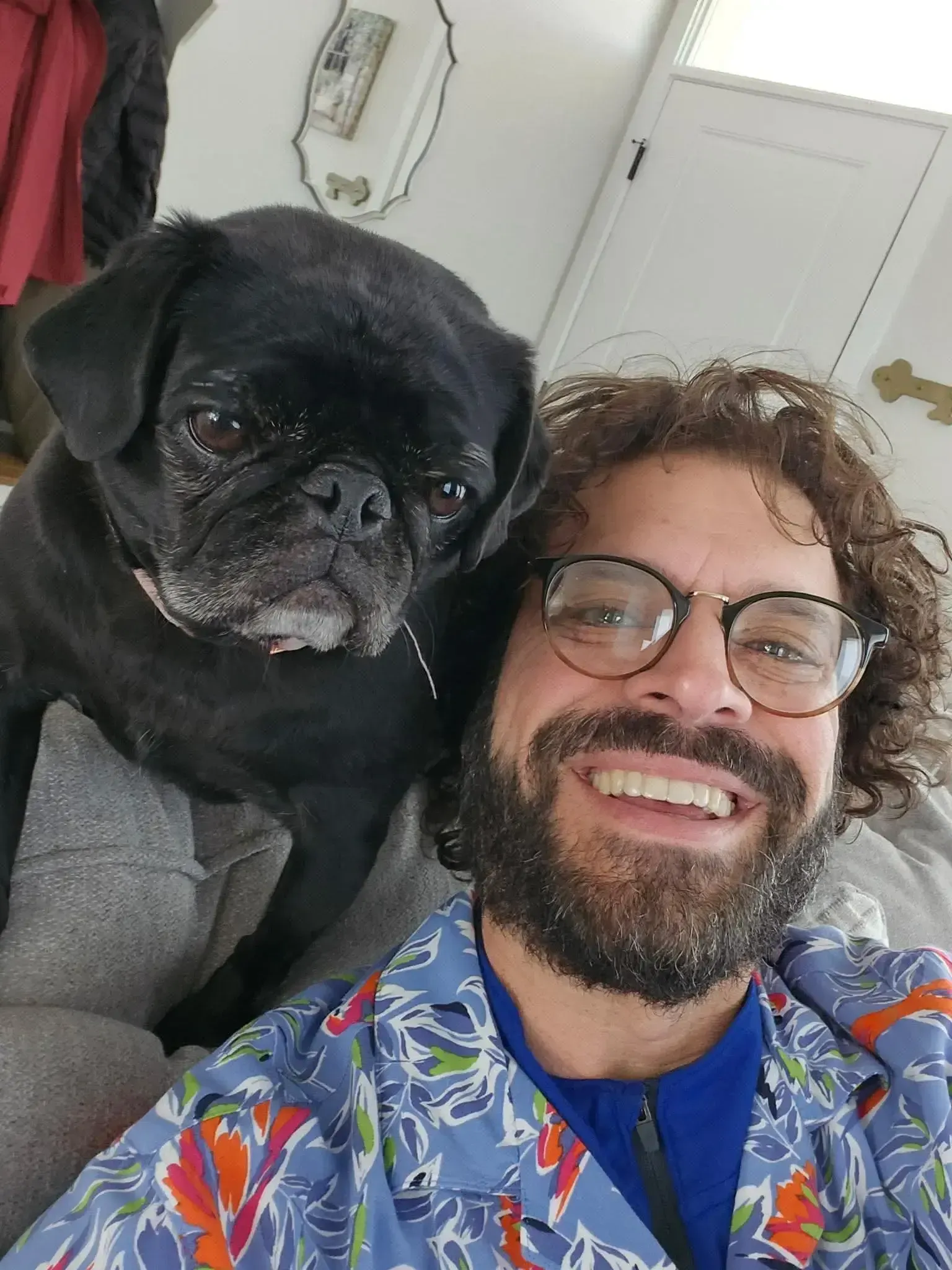 Jon sitting on a couch with his dog taking a selfie.