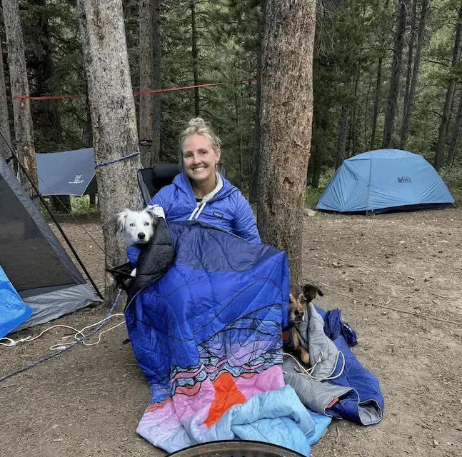 Professional pet sitter Kate sitting on a chair with a dog in a forest.