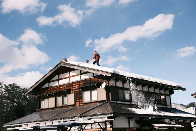 Traditional house with a person on the roof under a bright blue sky