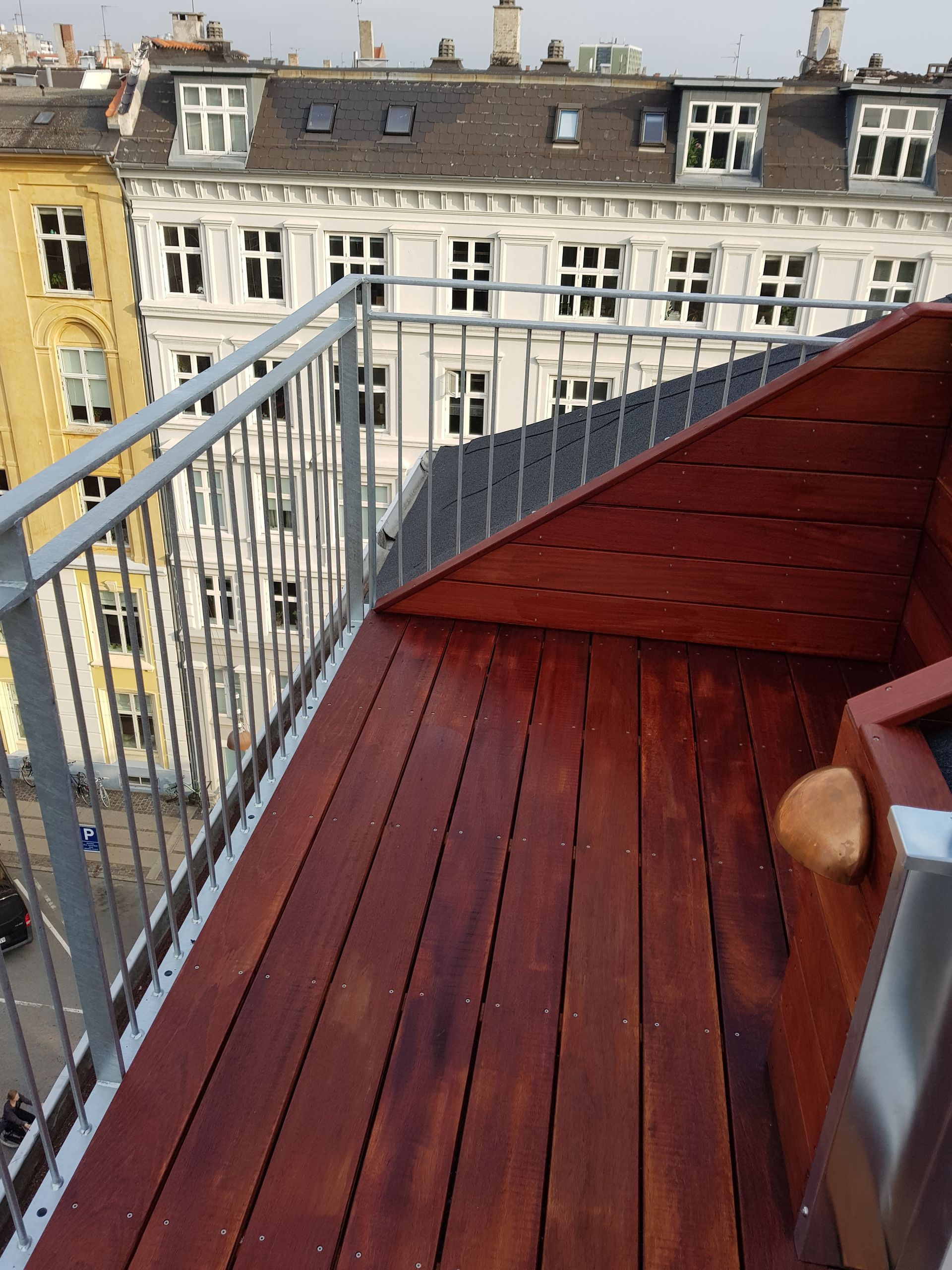 En balkon med et træterrasse og et metalrækværk