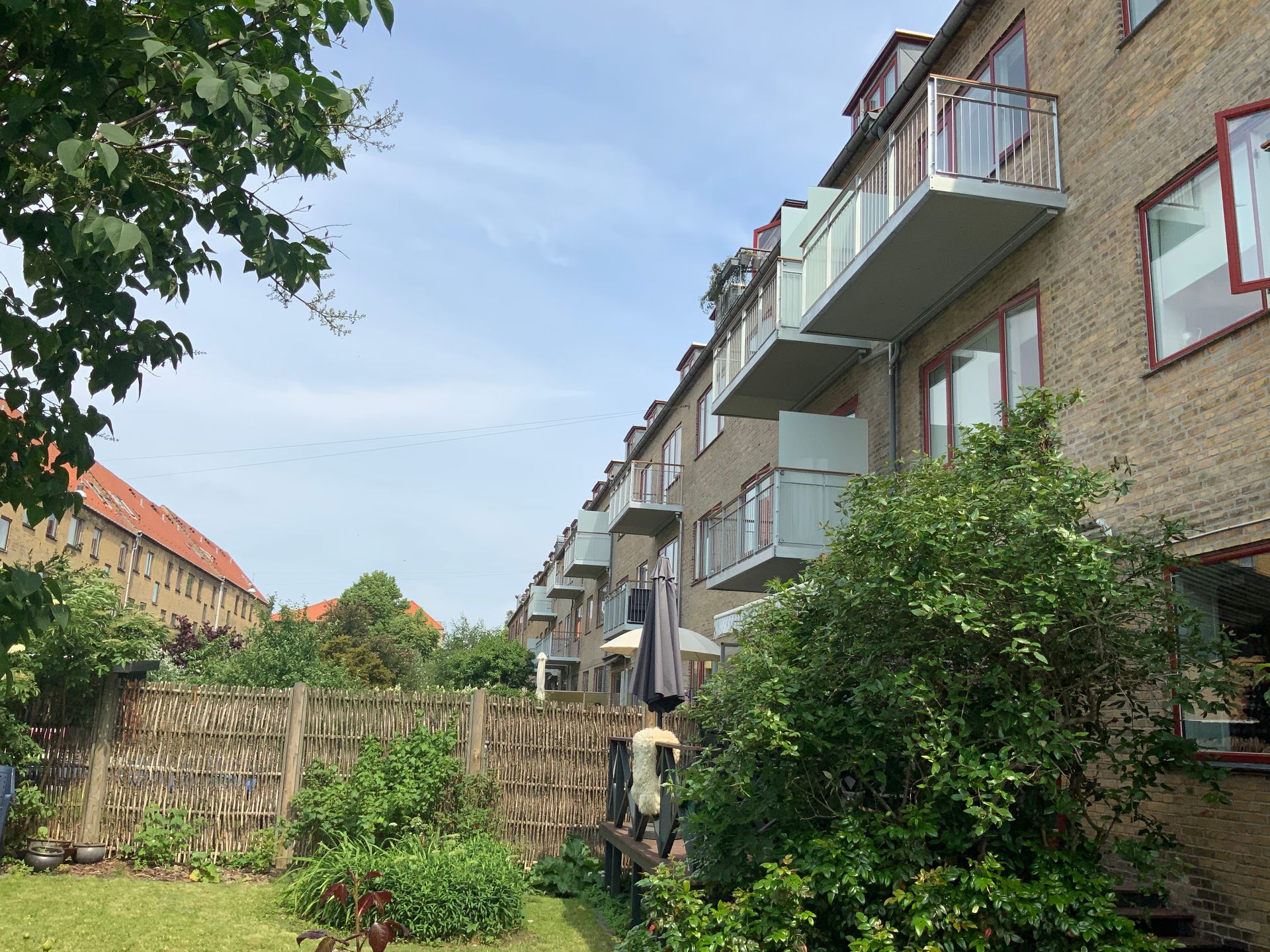 En murstensbygning med altaner og en have foran