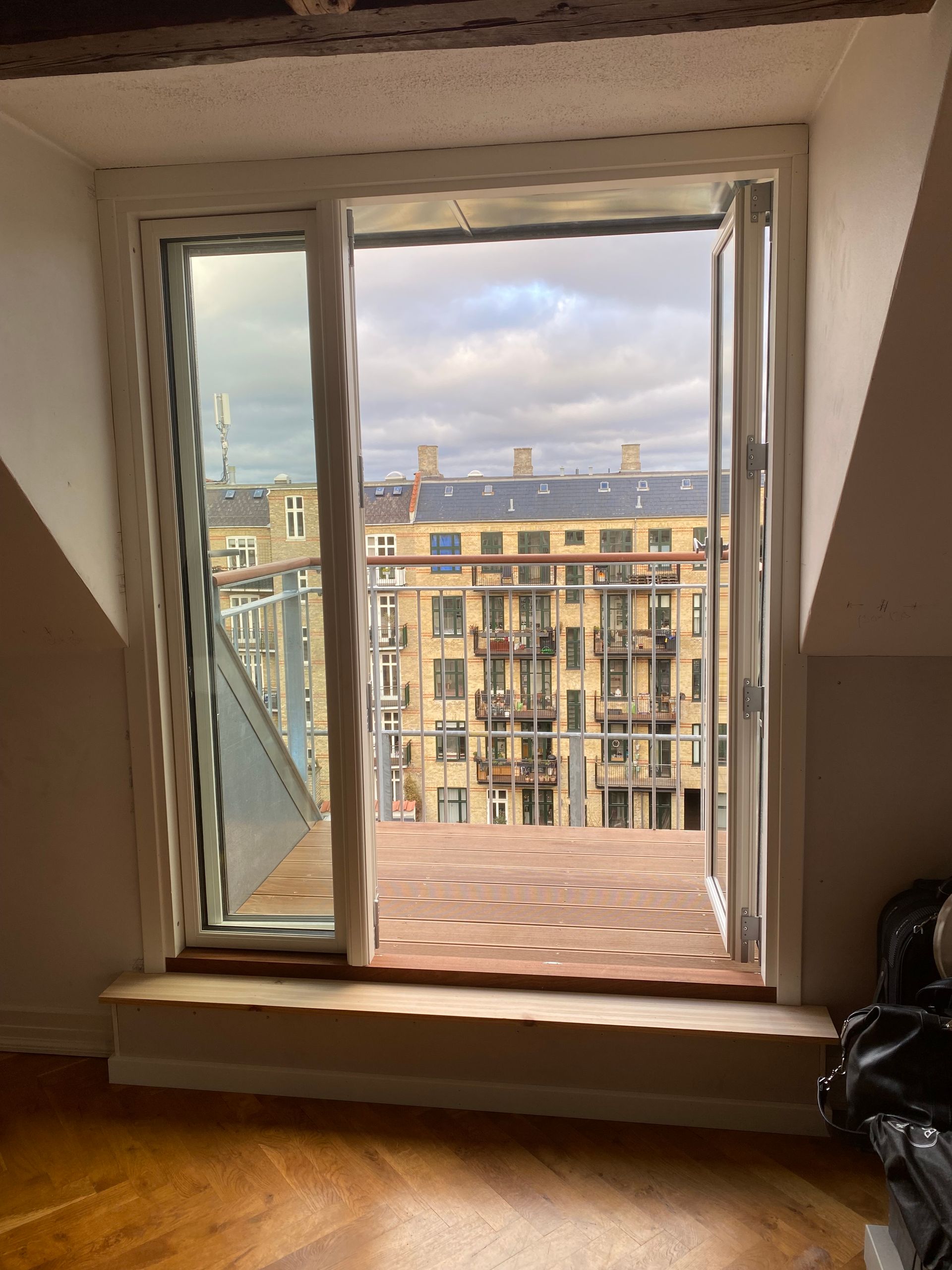 Et værelse med balkon og et vindue med udsigt over en by.