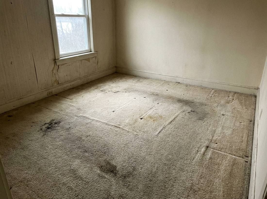 Worn, dated carpet in an empty room before a home sale