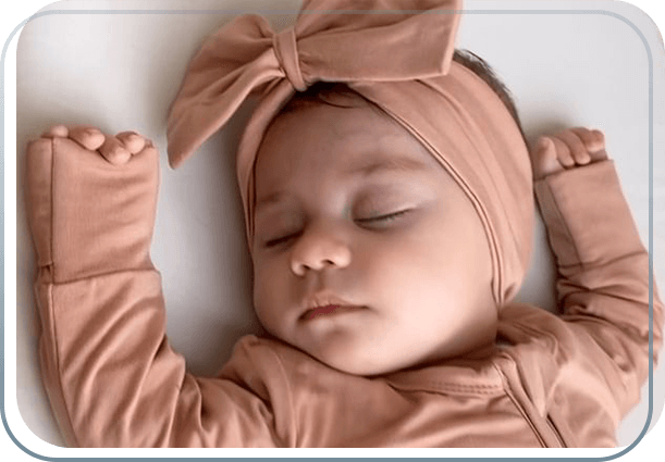 a sleeping baby wearing a Cuddly Suit