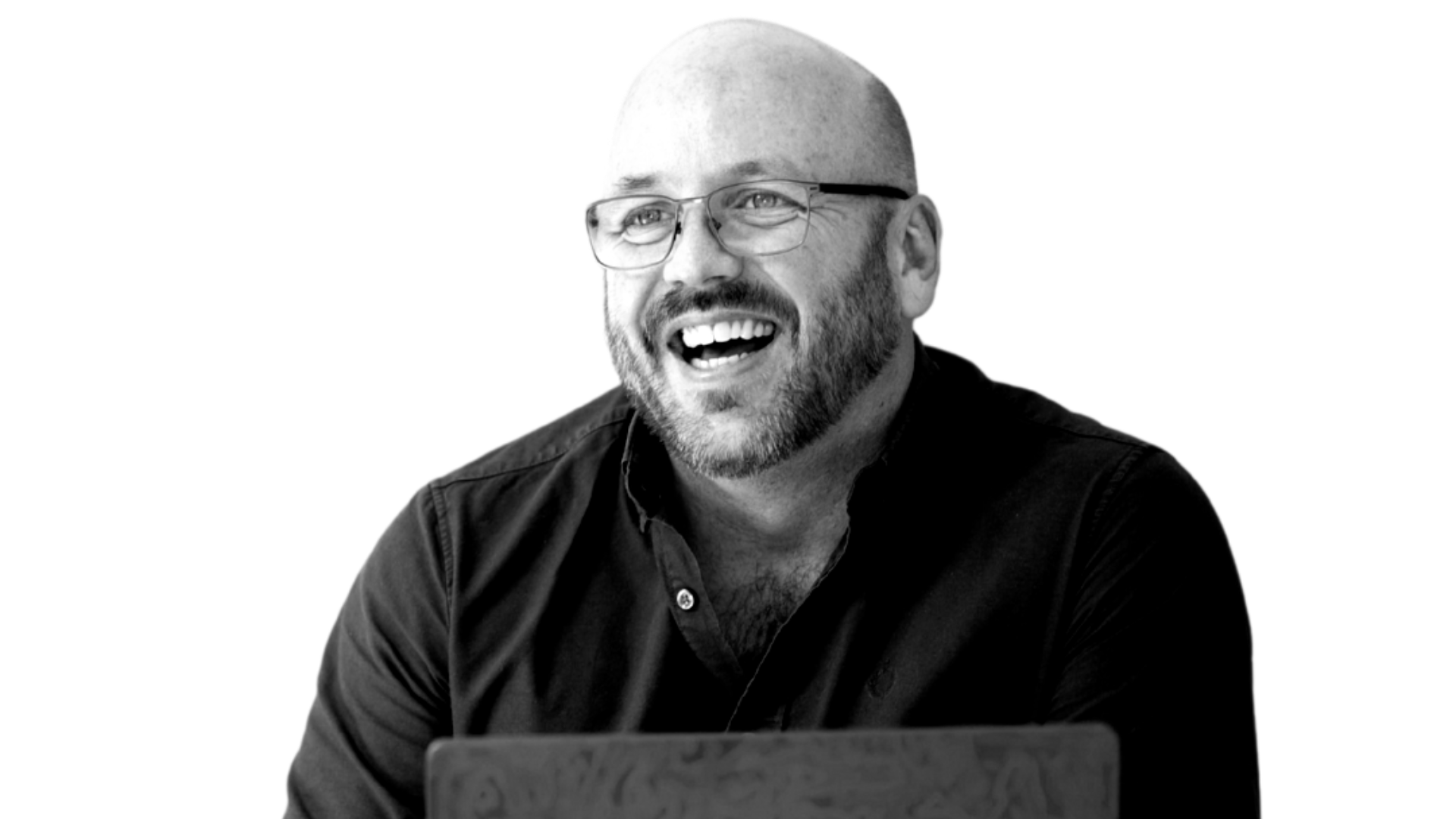Smiling bald man with glasses in a dark shirt, laughing against a white background