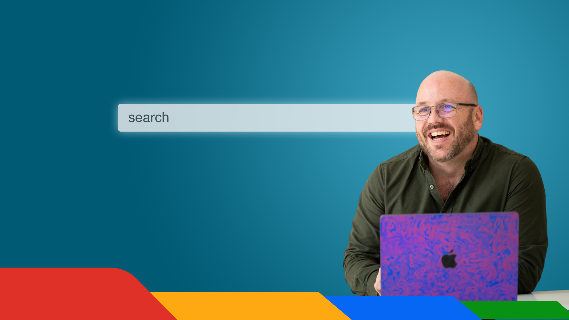 Man smiling beside a search bar, using a laptop on a teal background with colorful geometric shapes