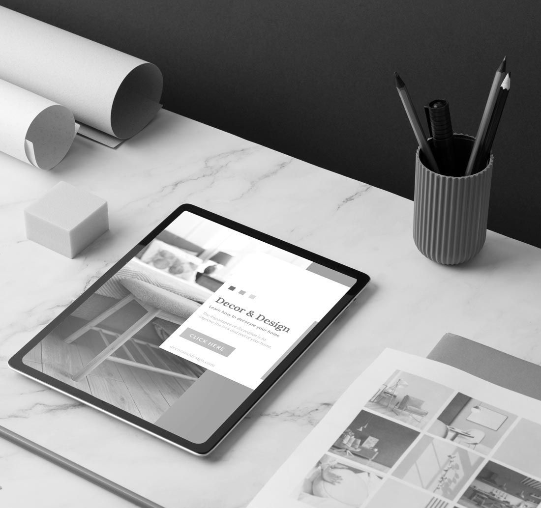Tablet on a marble desk beside rolled papers, a pencil cup, and an open magazine in a modern workspace