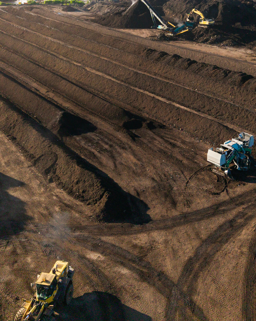 Excavators working on a large dirt slope at an open-pit mine