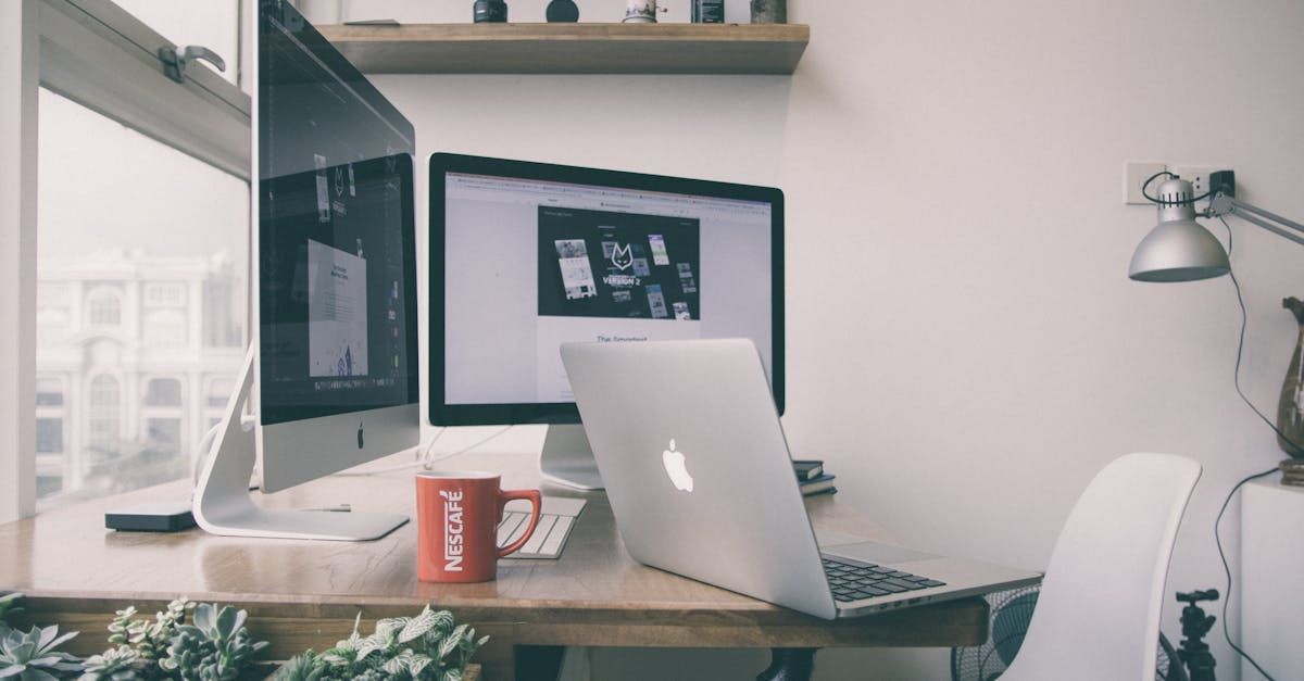 A desk with two computers and a laptop on it.