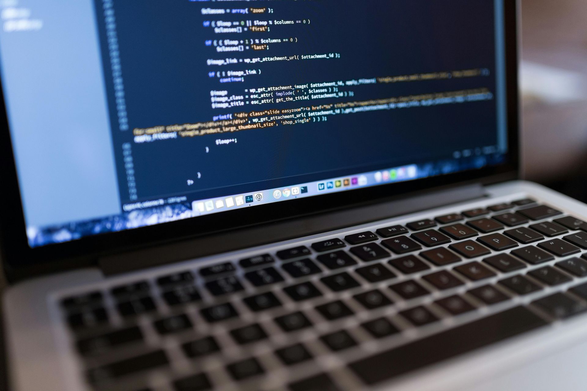 Laptop screen showing code in a dark-themed editor on a desk