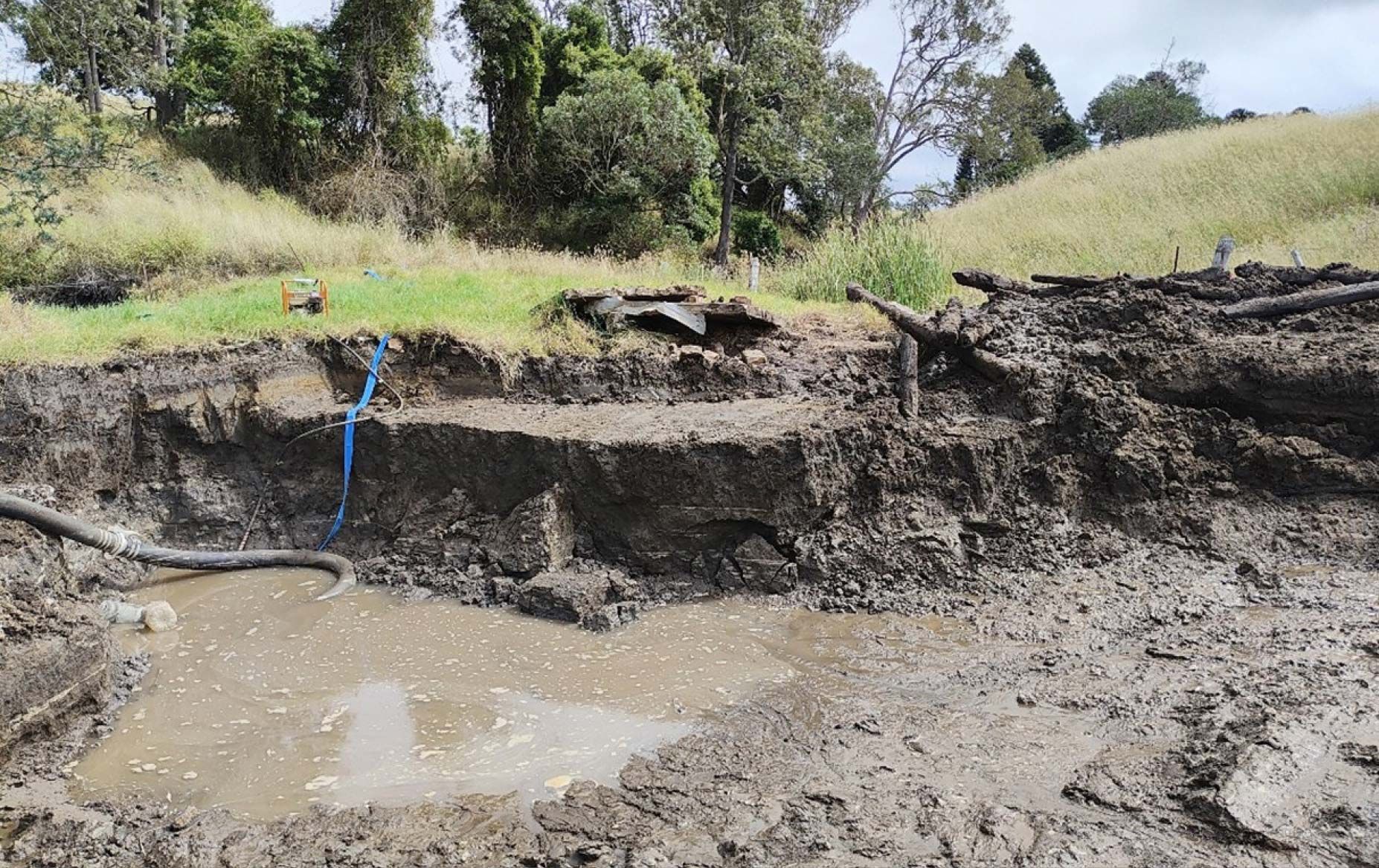 In March 2024, flood recovery excavation works on Petie Road, Anduramba revealed a subsurface alignment of timber logs, initially interpreted as refuse but later assessed as a probable historic corduroy roadway or timber bridge structure. The discovery was made approximately 1.5 meters below the surface, with associated artefacts including remnants of a steam boiler chimney. The site, measuring 20m x 14m adjacent to an active road corridor, presented archaeological potential requiring formal notification under section 89 of the Queensland Heritage Act 1992. Excavation ceased and Redleaf Group was engaged to record and report the find.
