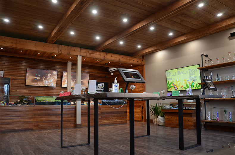 Interior of a cannabis dispensary, with wood paneling, displays, and products on tables.
