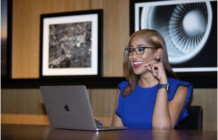 A woman is sitting at a table using a laptop computer.