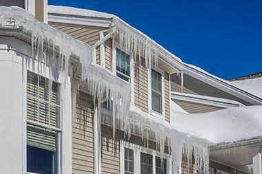 Icicles are hanging from the roof of a house.
