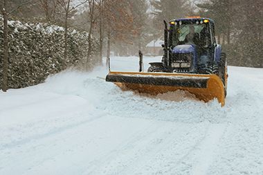 A tractor is plowing snow on a snowy road.