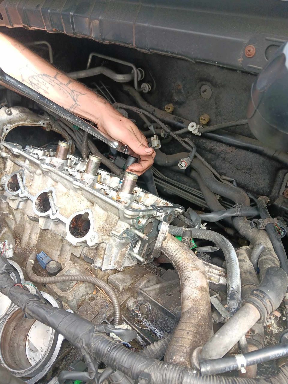 Hand working on an engine, with exposed parts and hoses.