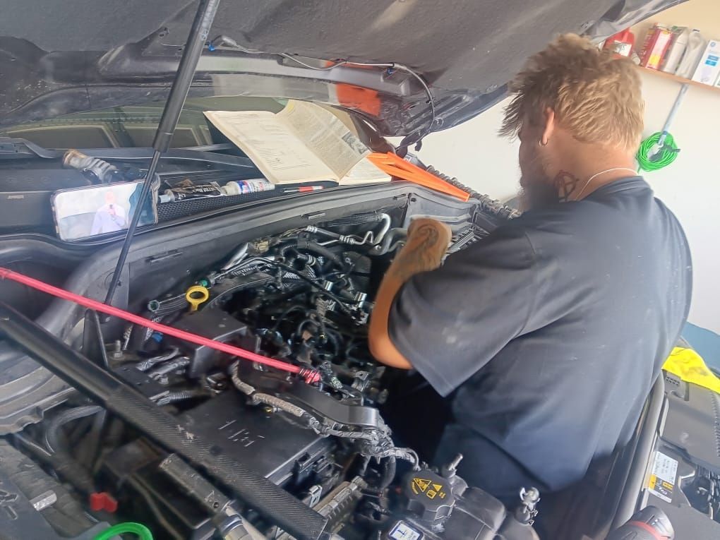 Man working on a car engine with the hood open.
