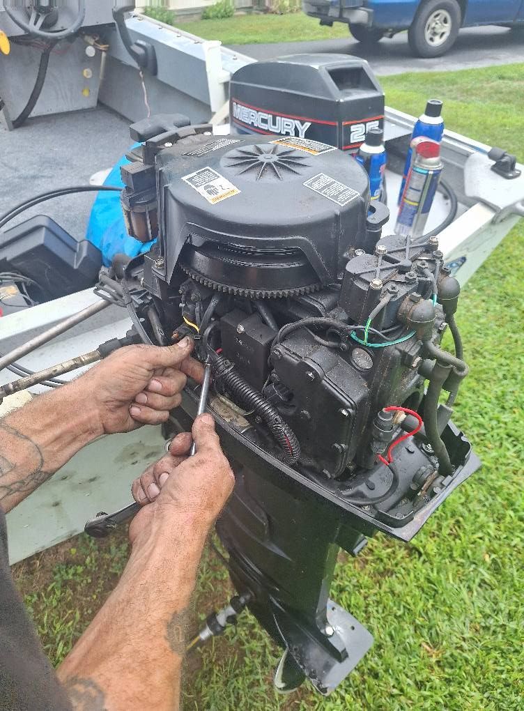 Person using a wrench to work on a black outboard boat motor.