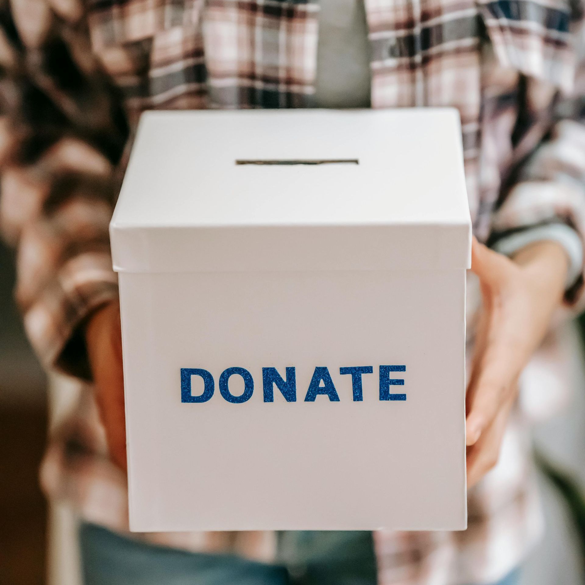 Person holding a white donation box with