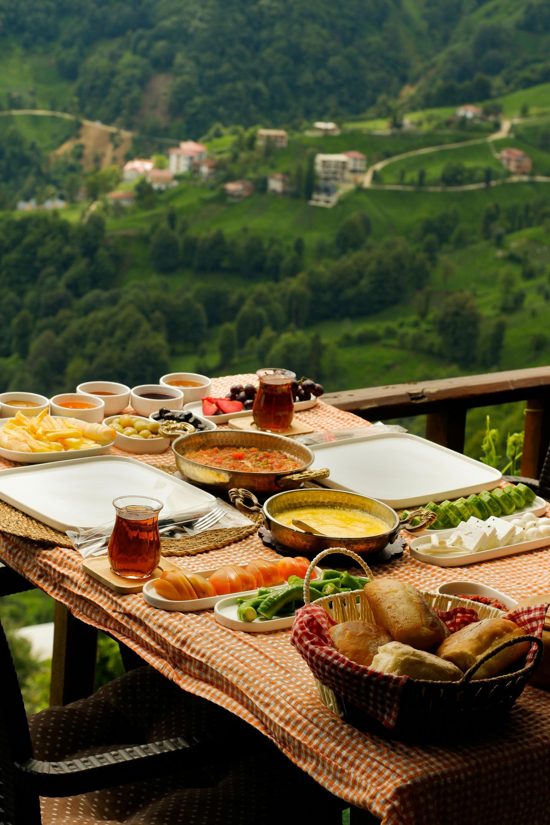 Breakfast spread on a terrace table overlooking a green mountain valley