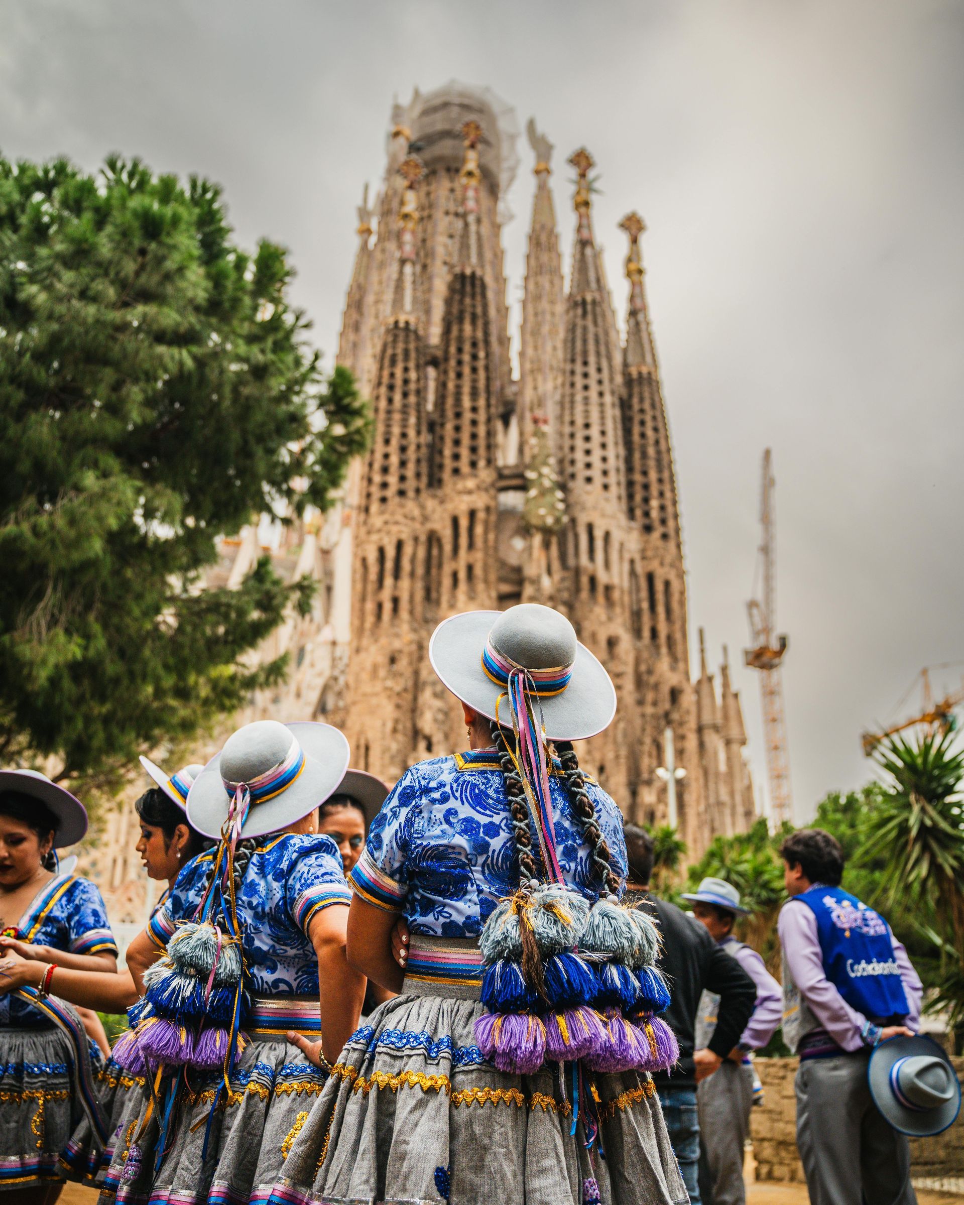 People in blue costumes dancing before the Sagrada Família in Barcelona