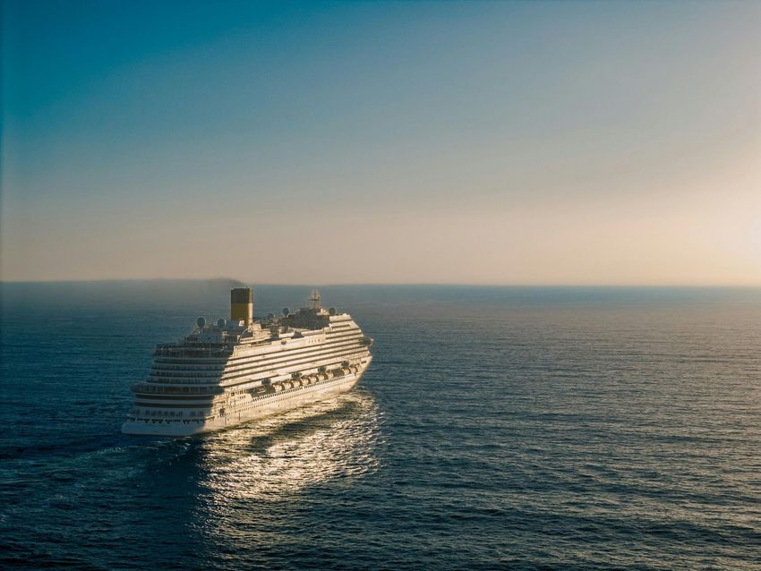 Large cruise ship sailing on a calm blue ocean at sunset