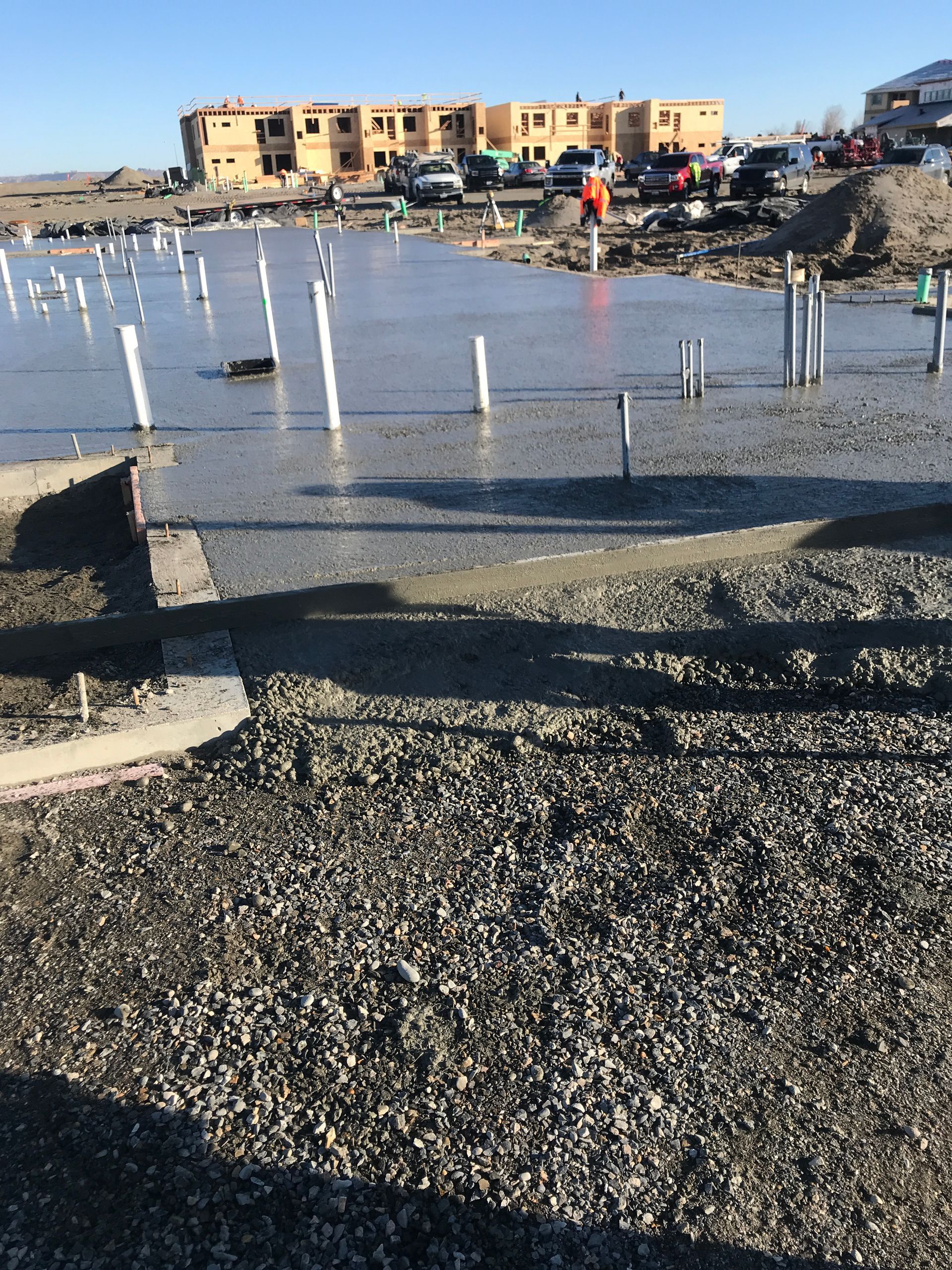 Flooded construction site with white posts, rubble, and tan buildings in the background