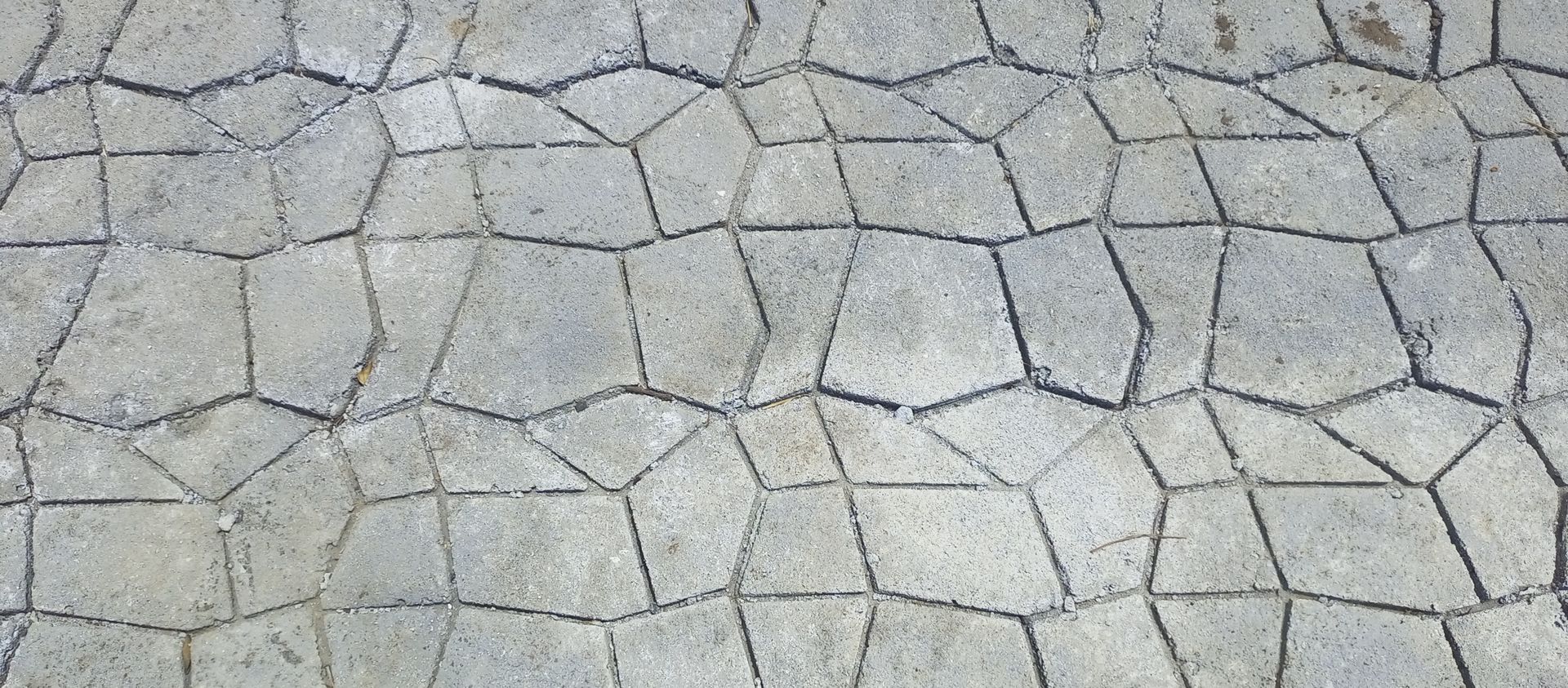 Cracked light gray stone pavement with irregular polygon tiles