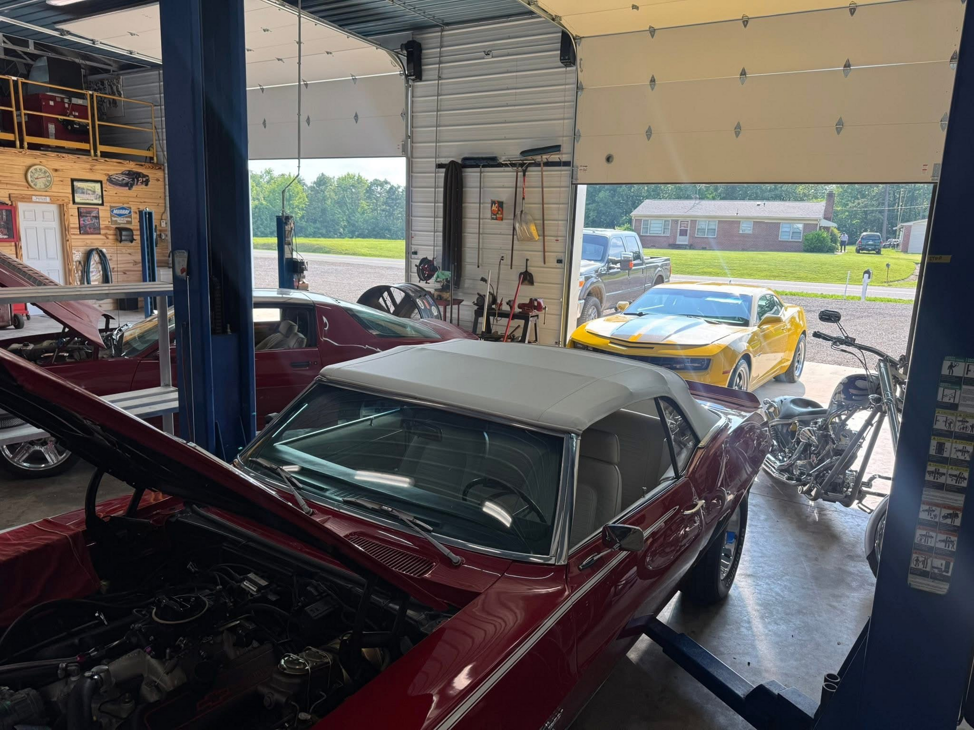 Cars in a garage, a red convertible on a lift, a yellow Camaro outside | Chip Ragans Auto, LLC