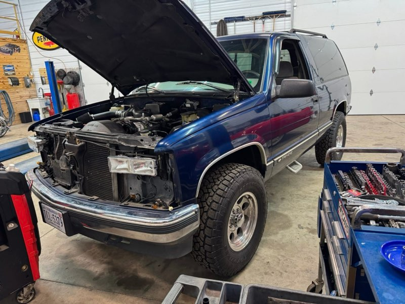 Blue Chevy SUV with open hood in a garage | Chip Ragans Auto, LLC