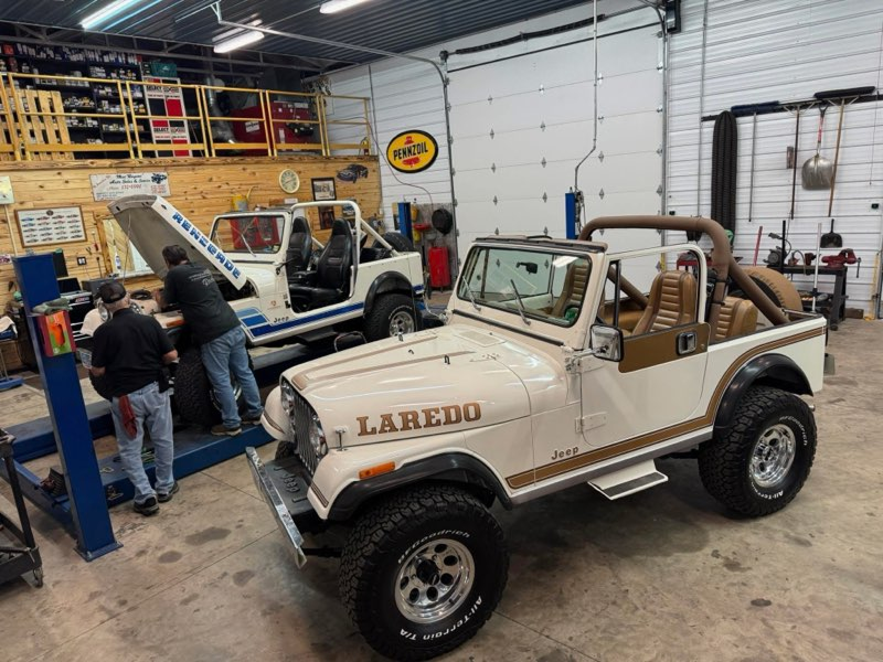 Two classic Jeeps in a garage; a white 