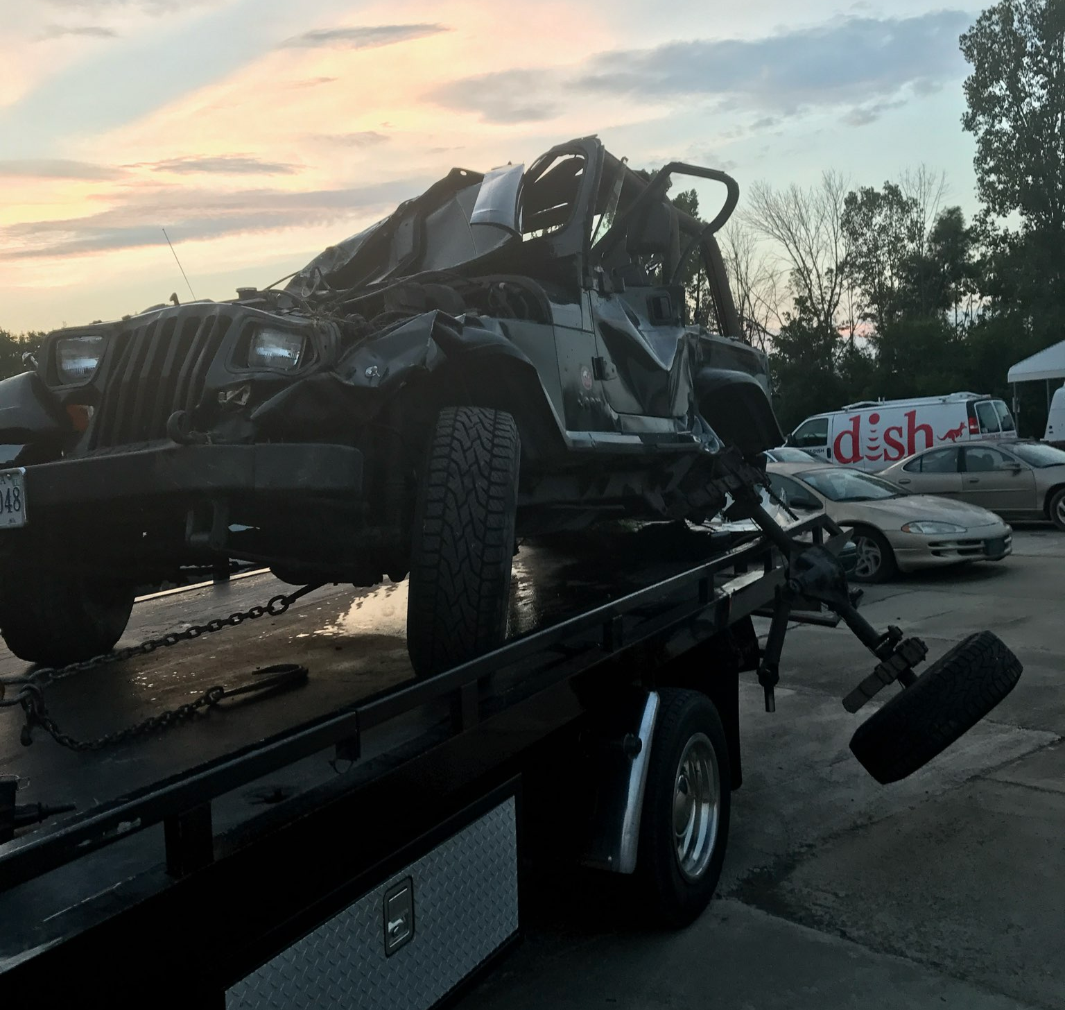 Damaged Jeep on a tow truck after a car accident; evening setting | Chip Ragans Auto, LLC