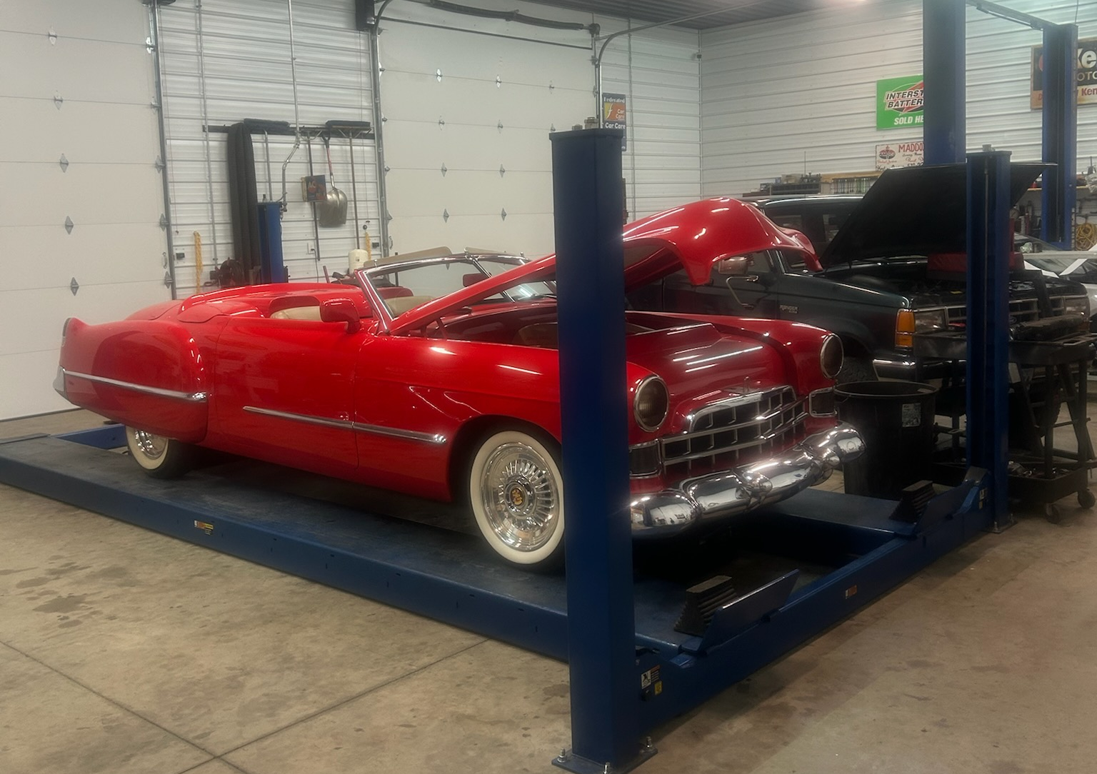 Red classic car on a blue auto lift in a garage. Another car is partially visible behind it | Chip Ragans Auto, LLC