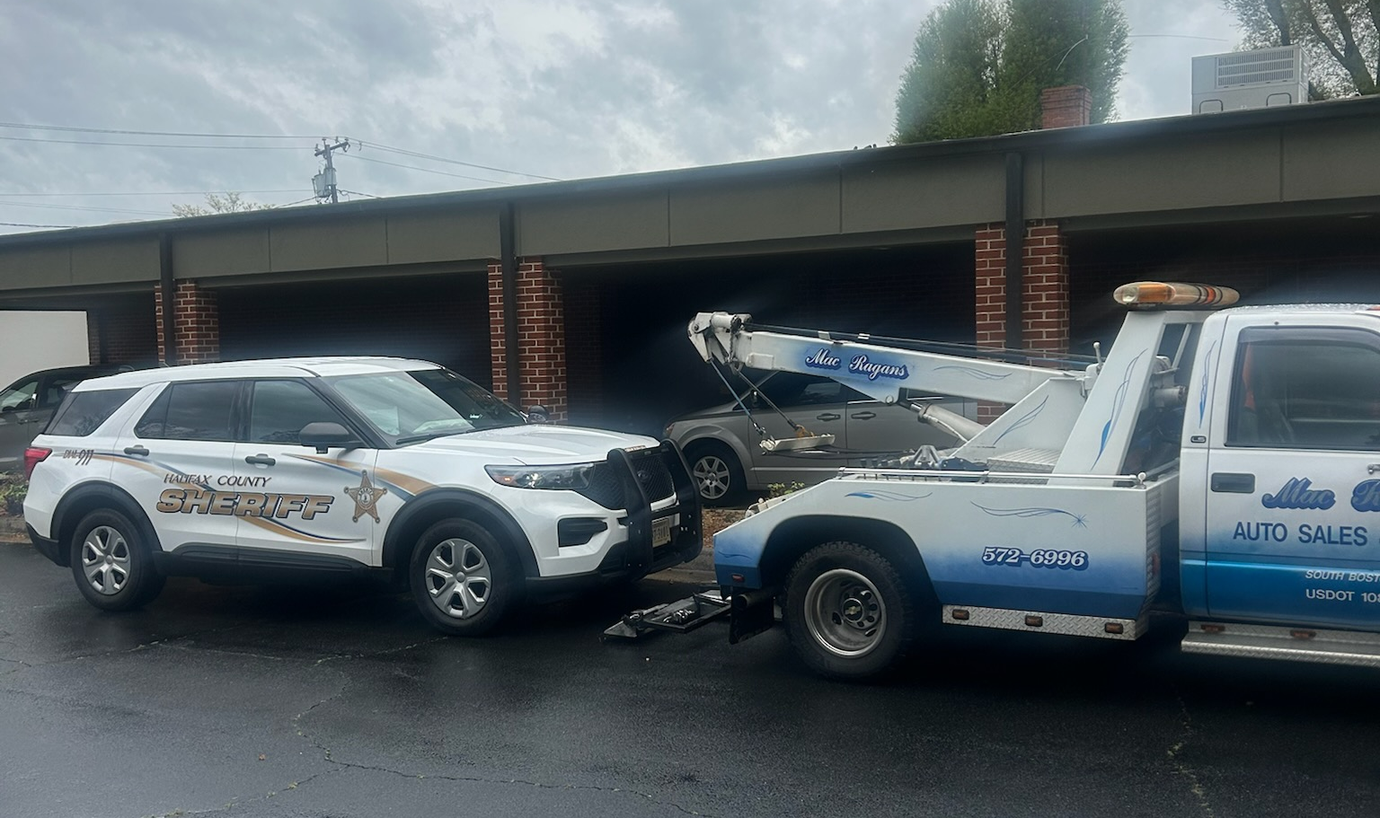 Sheriff's SUV being towed by a tow truck. Scene is in front of a brick building | Chip Ragans Auto, LLC