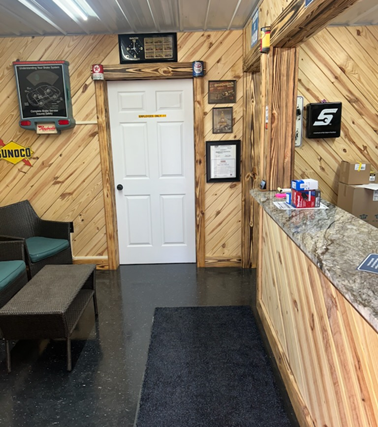 Interior of an auto repair shop with wood paneling, a white door, and a front counter | Chip Ragans Auto, LLC