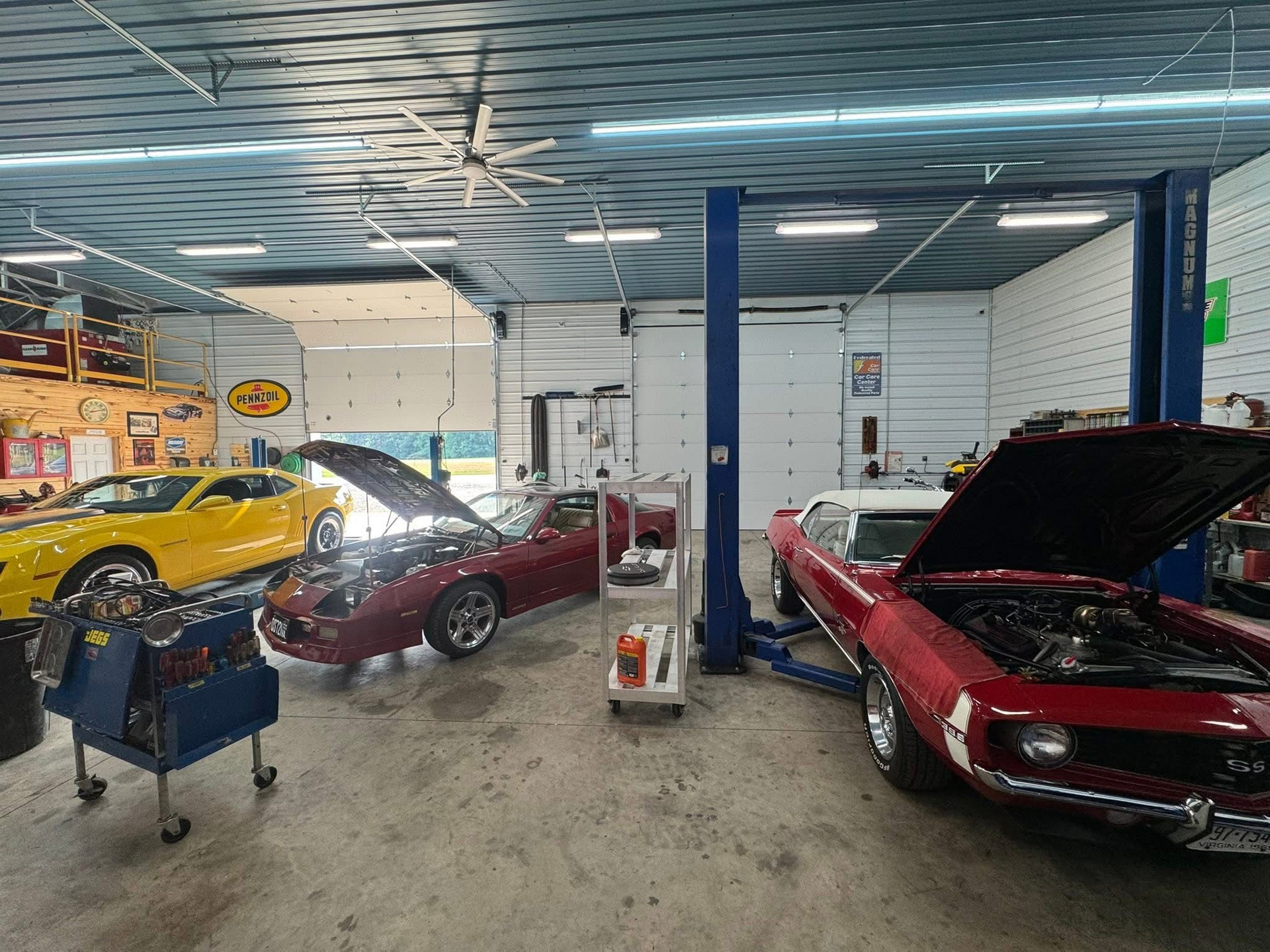 Classic cars inside a garage with open hoods. Tools and a car lift are also visible | Chip Ragans Auto, LLC
