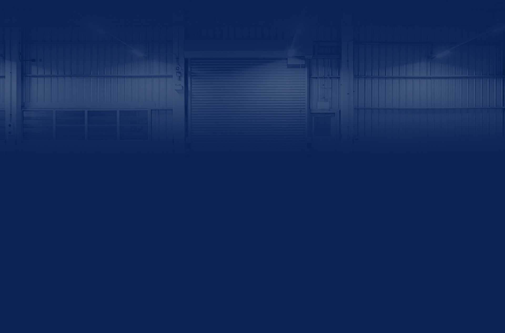 Warehouse interior with large closed roller door, blue tone | Chip Ragans Auto, LLC