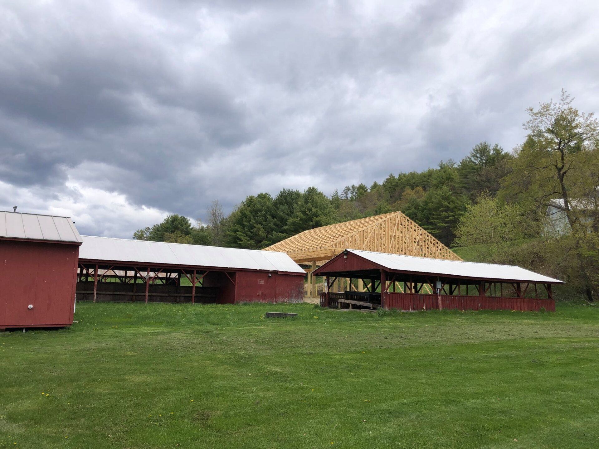A group of red buildings are sitting on top of a lush green field.