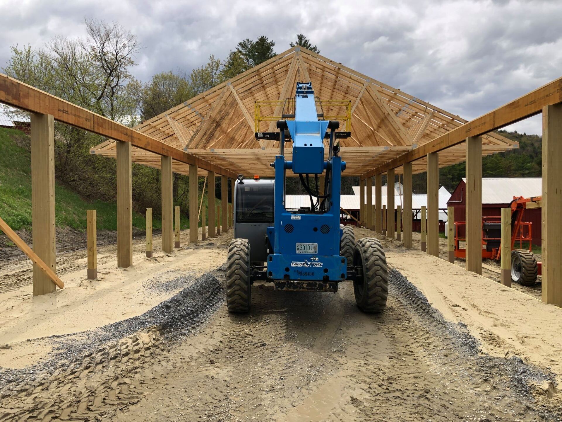 A blue forklift is parked in front of a building under construction.