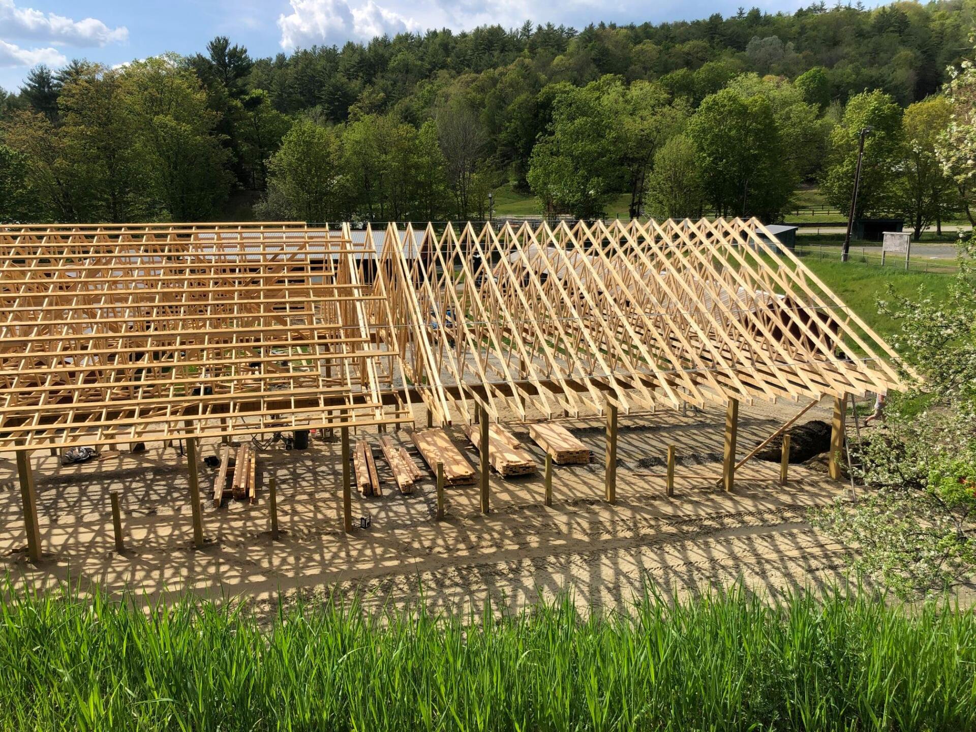 A large wooden structure is being built in a field.