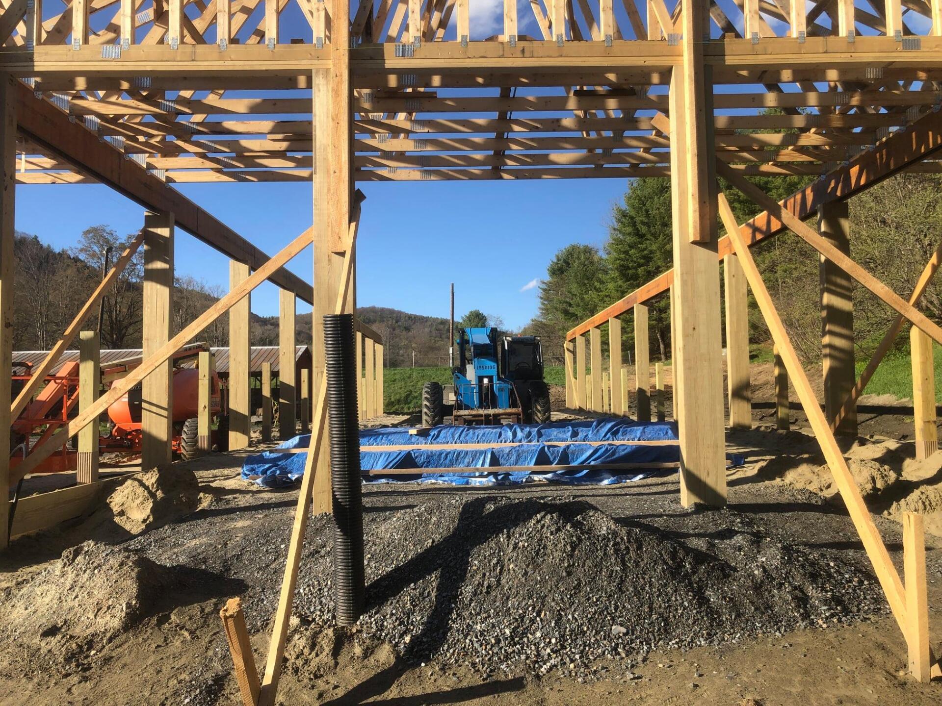 A blue tractor is driving through a building under construction.
