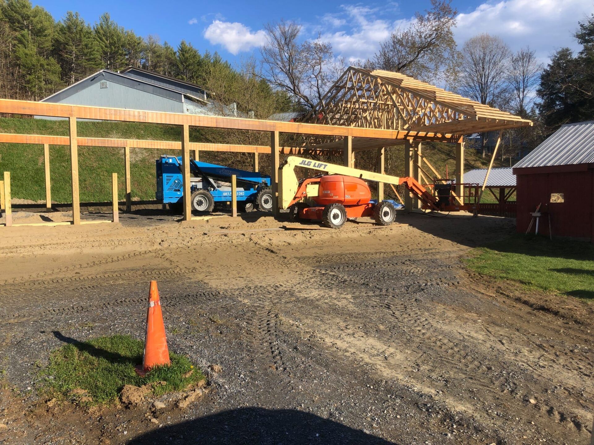 A row of construction vehicles are parked in front of a building under construction.