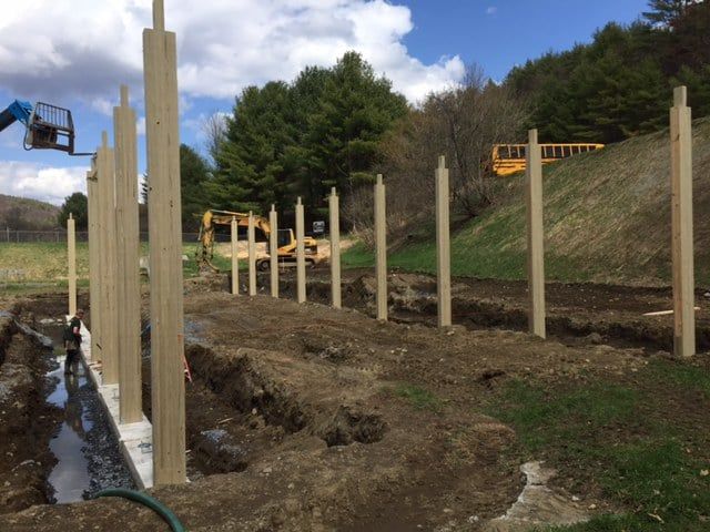 A wooden fence is being built in a dirt field.