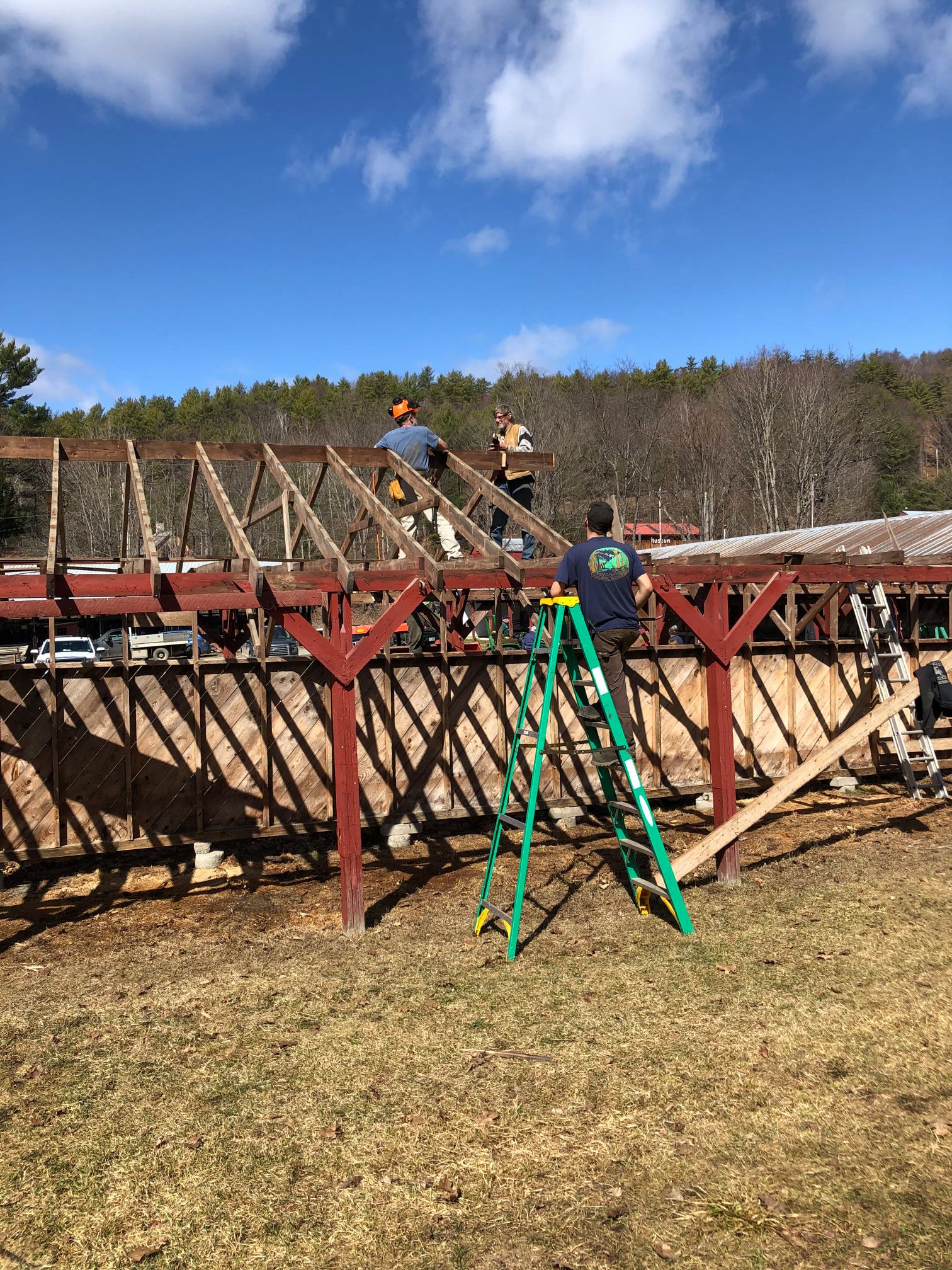 A group of people are working on a wooden structure in a field.