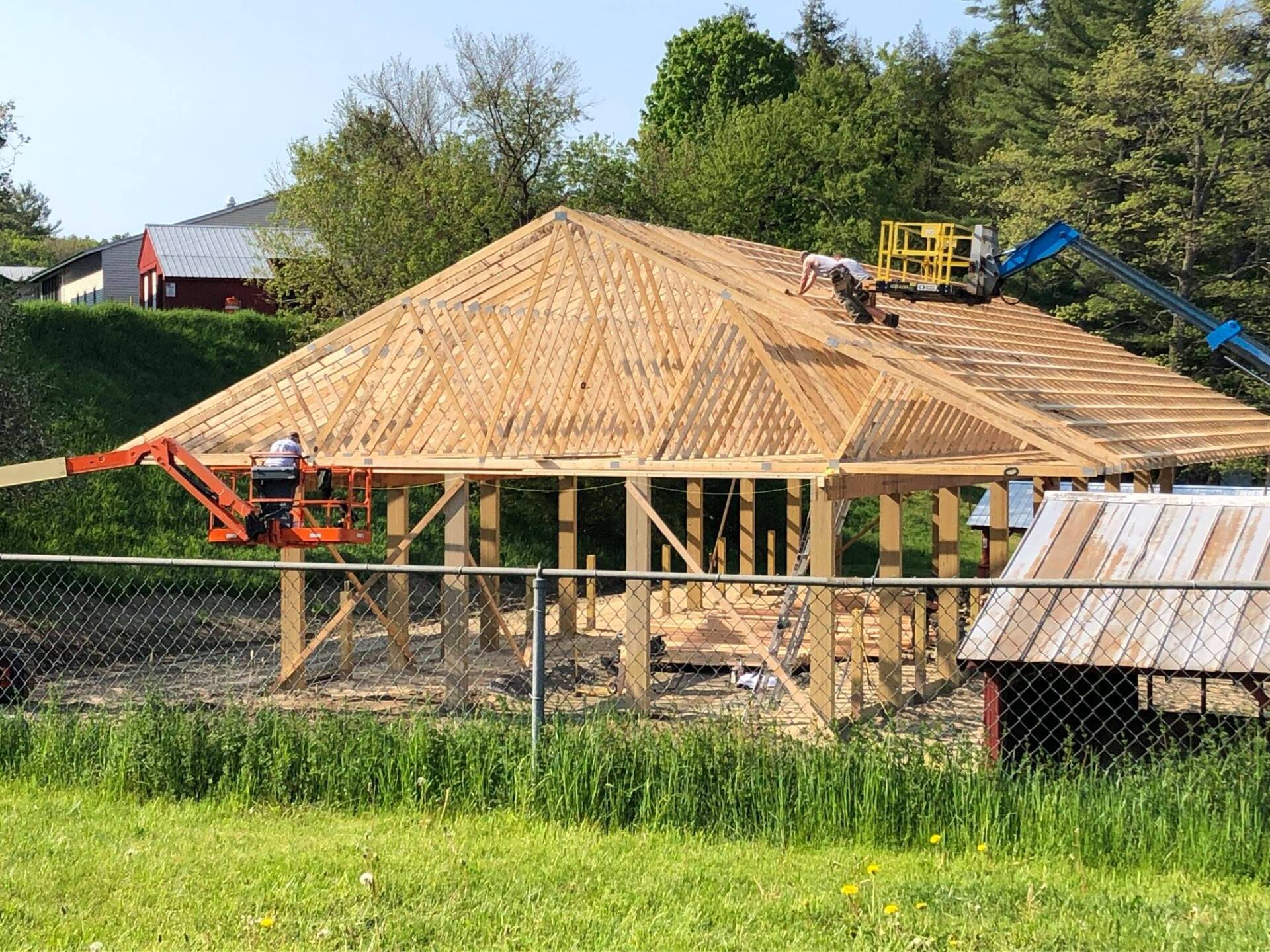 A large wooden structure is being built in a grassy field.